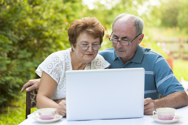 Una pareja de adultos mayores con una computadora.